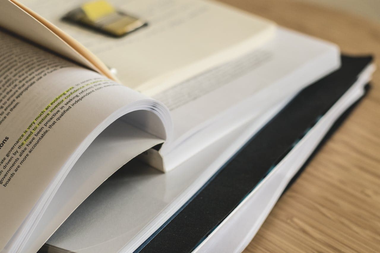 Open textbook on a desk next to a laptop